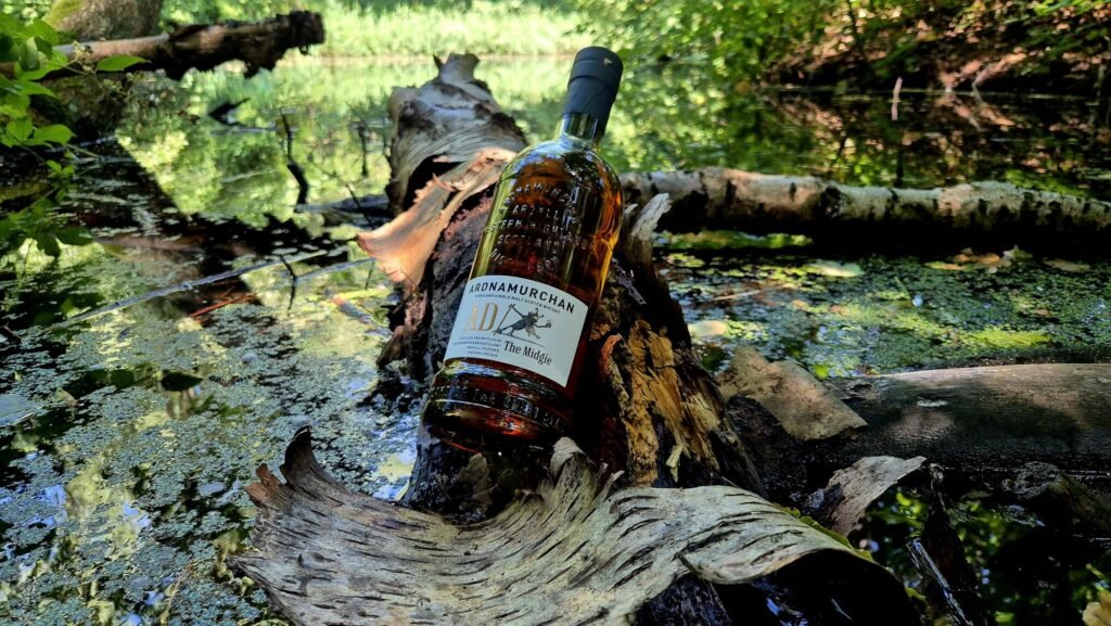 A bottle of Ardnamurchan The Midgie 2025 release sitting near the waterfront.
