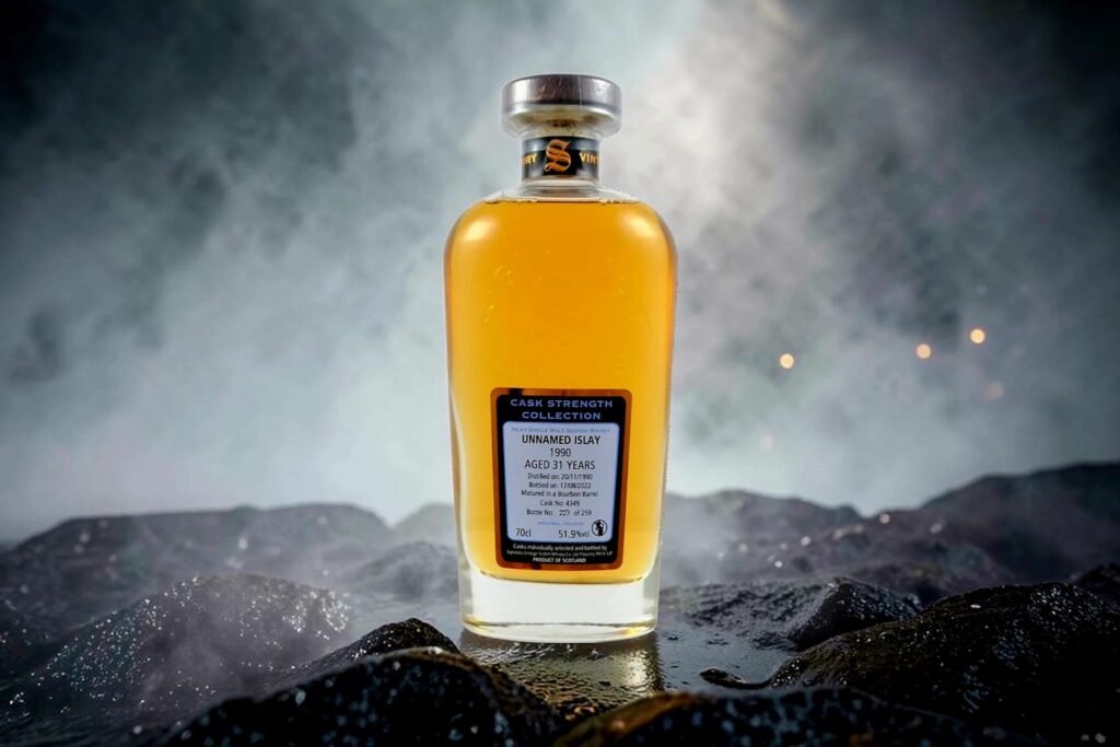 Signatory Unnamed Islay 1990 31-year-old cask strength whisky bottle (Cask 4349) standing on dark rocks with mist and smoke in the background