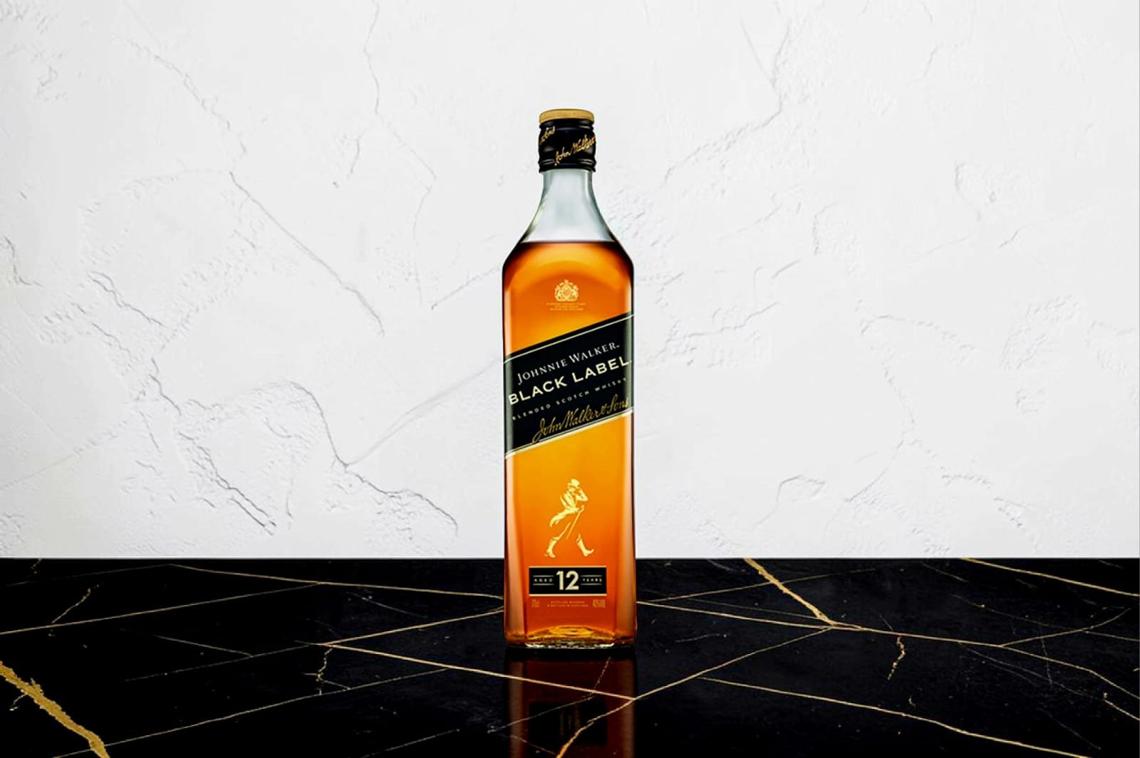 Johnnie Walker Black Label 12 Year Old whisky bottle on a dark marble surface with gold veining