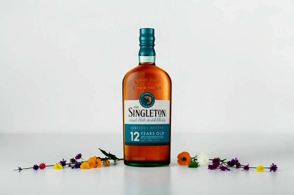 Scattered flowers in soft natural light partially revealing a bottle of Singleton 12 whisky, styled for a Singleton 12 review image