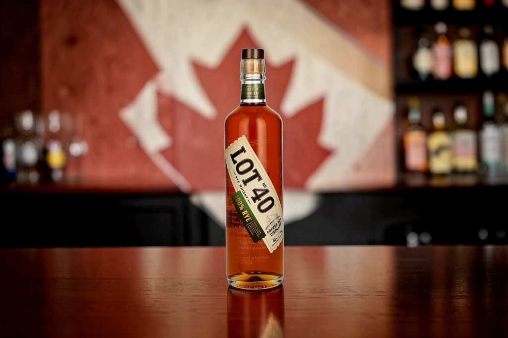 Lot No. 40 Canadian Rye Whisky bottle displayed on a wooden bar with a Canadian flag backdrop.